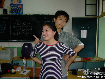 照片是一女生和一个男生在学校教室的合影
