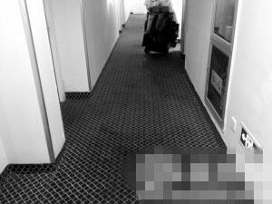 酒店走廊上，灰色地毯上遗留有血迹。