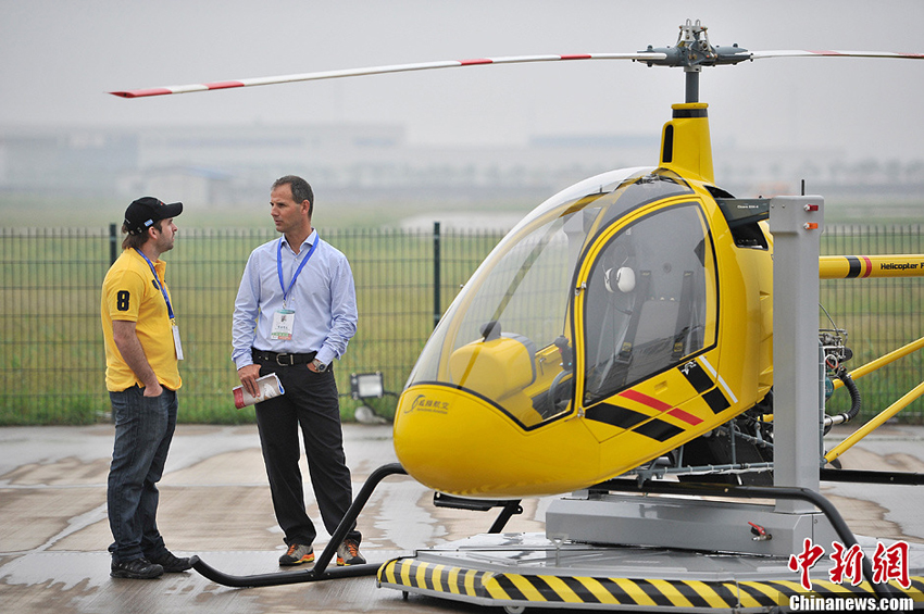 2013年9月5日，两名参展商在台湾威翔航空科技股份有限公司生产的SVH-4培训直升机旁交谈。图片：中新社发（摄影：佟郁）