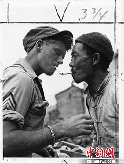 1944年10月14日，一位年长的中国男人在满目疮痍的云南那腾冲街头停下来，向一名美军军士借火，点燃他的烟锅。　资料图　摄