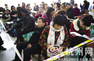 拱墅区青少年宫，一名排队拿报名号子的家长在打毛线。记者 朱丹阳 摄