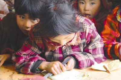 在村小的教室里，吉觉阿呷帮低年级学生削铅笔。记者　张文摄
